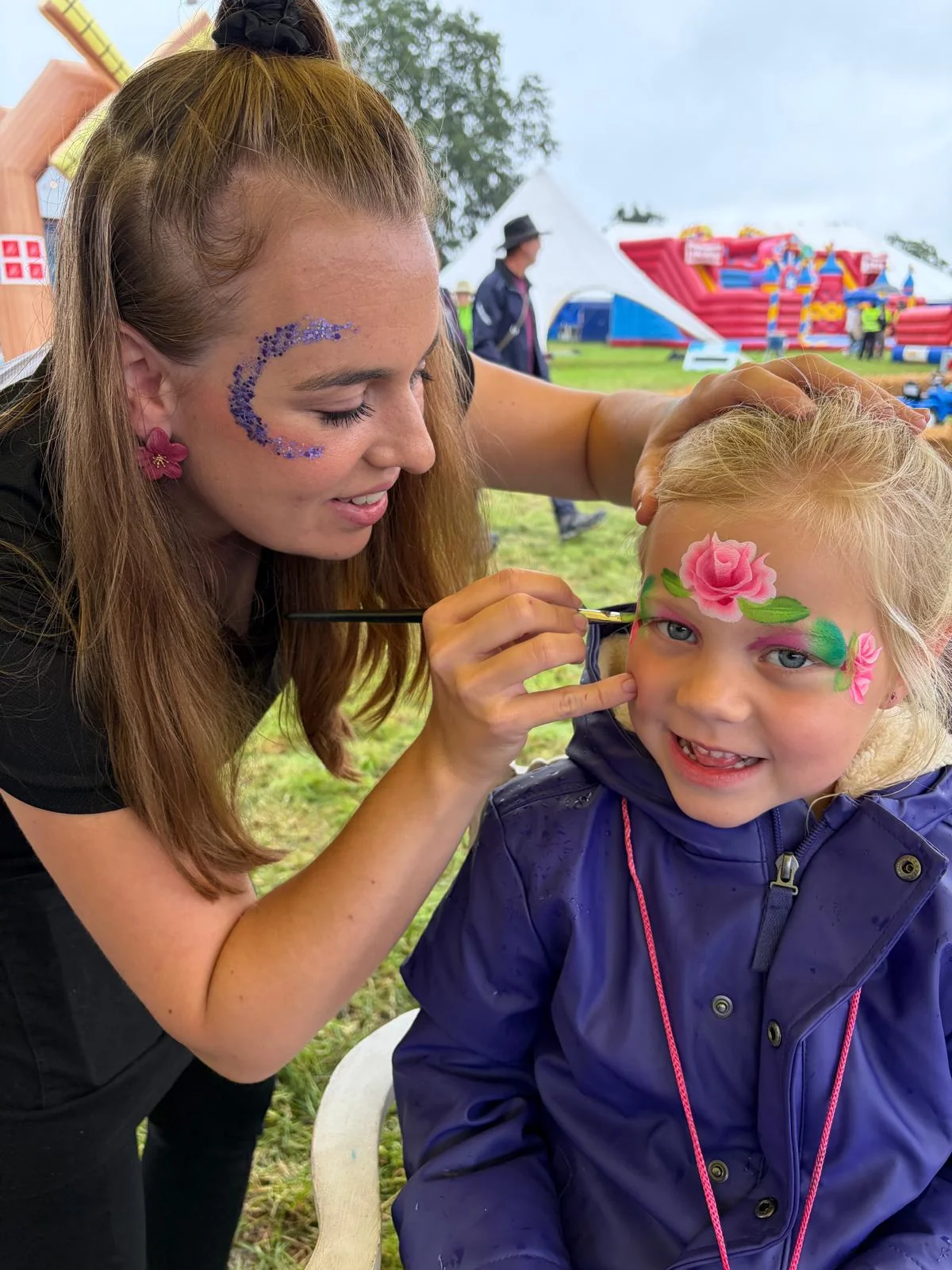 Linda van Schminkplezier schminkt een kind met een roze roos tijdens een feest