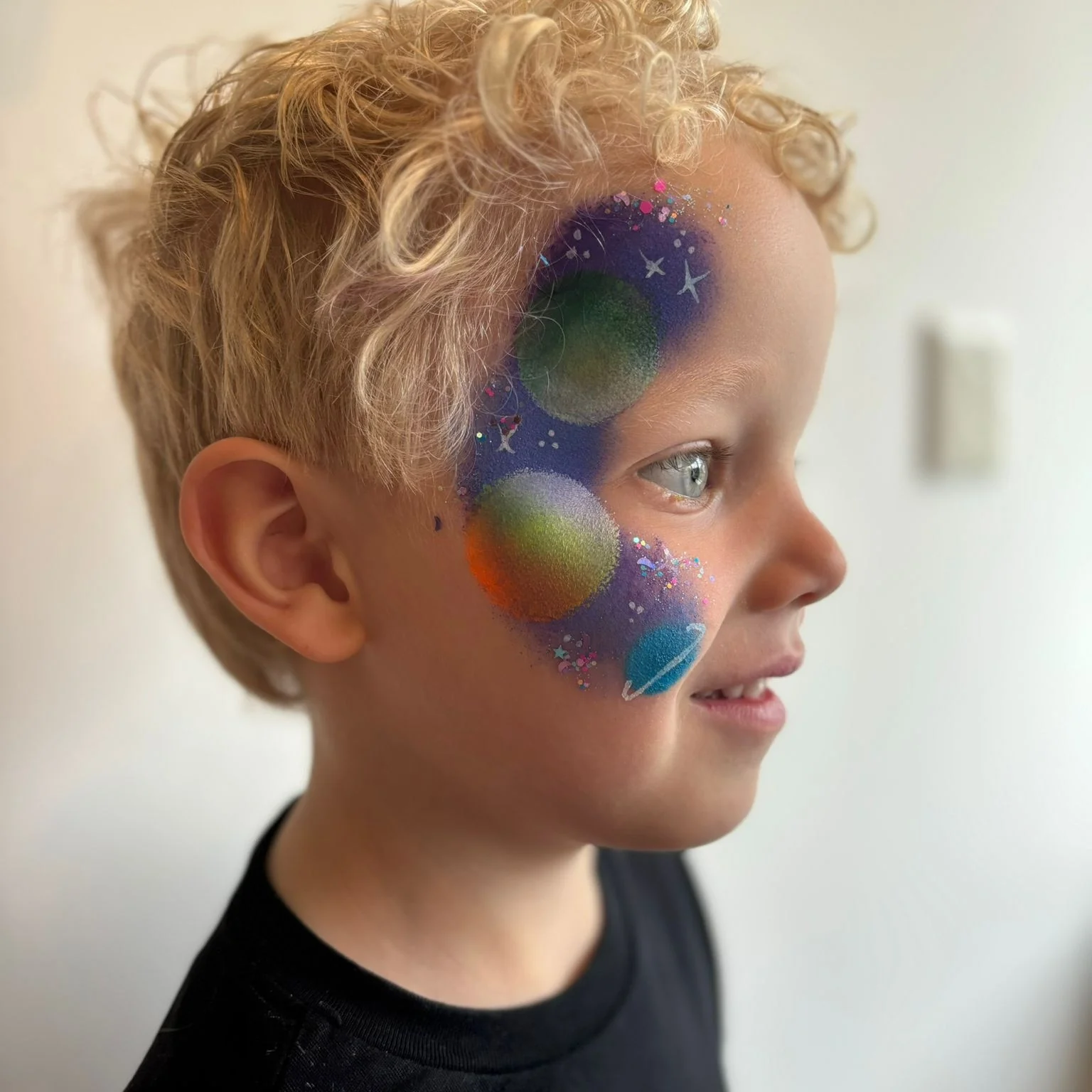 Kind met kleurrijke planeten en sterren geschminkt op de wang